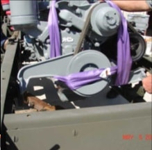 Close-up of engine with purple straps being lowered into halftrack