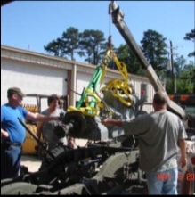 Team lowering engine into halftrack with crane and straps