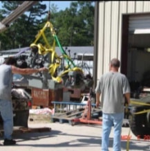 Workers steadying engine during installation process