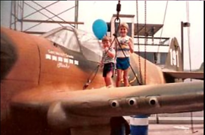Child standing beside P-40 Warhawk nose art